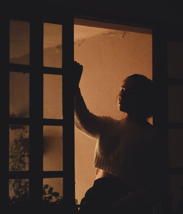 Person meditating peacefully in a room with soft, warm light coming from a window.